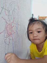 Portrait of cute girl drawing on wall