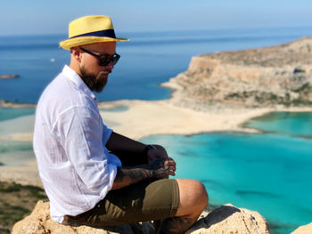 Man sitting on rock by sea