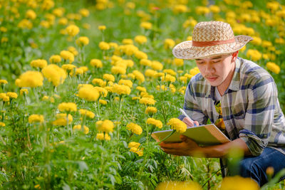 Man holding yellow flowers in field