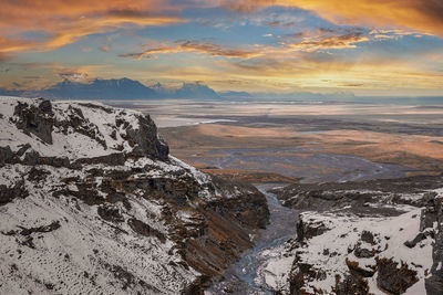 Beautiful view of stream amidst snow covered mountains in valley during sunset