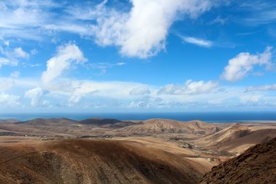 Scenic view of desert against cloudy sky