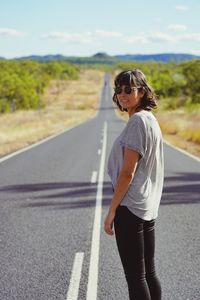 Young woman wearing sunglasses standing on road