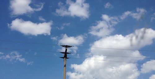 Low angle view of electricity pylon against cloudy sky