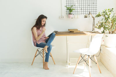 Woman sitting on chair by table at home