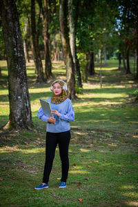 Young woman with laptop listening music in park