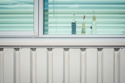 Small flowers in bottles behind glass window