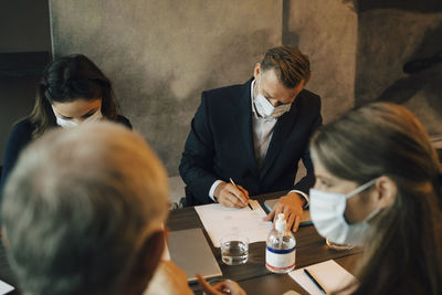 Business people discussing over document during meeting at board room in office