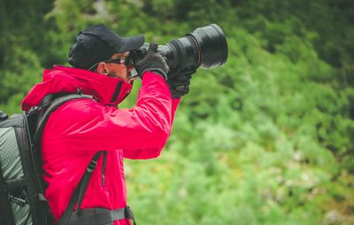 Side view of man photographing in forest