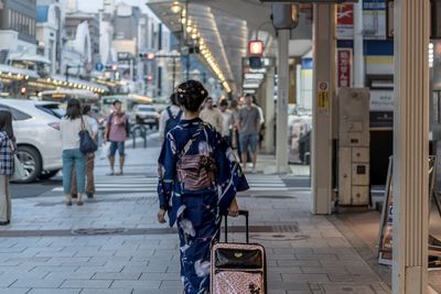 Rear view of woman in traditional clothe walking on street in city, going to travel 