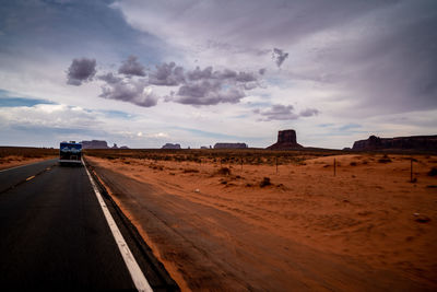 Road amidst desert land against sky