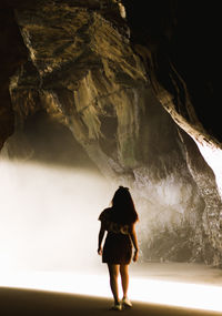 Rear view of woman standing in cave