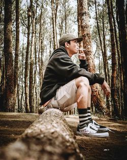 Young man sitting on rock in forest