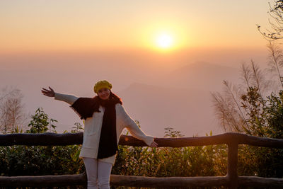 Portrait of smiling woman standing against sky during sunrise