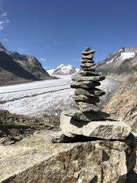 Stack of rocks on mountain against sky with glacier