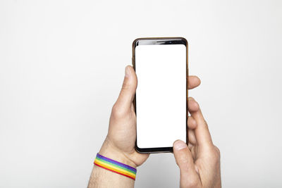 Hand with gay pride bracelet holds smart phone with blank screen. isolated on white background