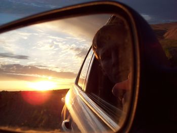 Woman in side-view mirror of car