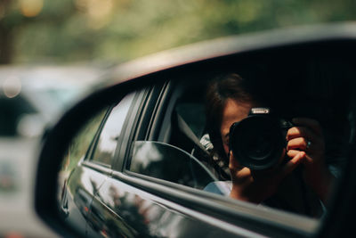 Reflection of man photographing car