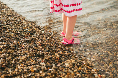 Low section of little girl standing on pebbles