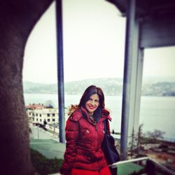 Portrait of smiling young woman standing against sky