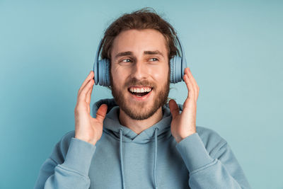 Portrait of young man using smart phone against blue background