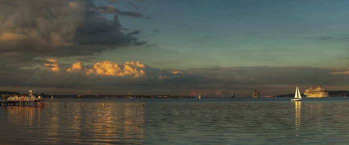 Sailboats in sea at sunset