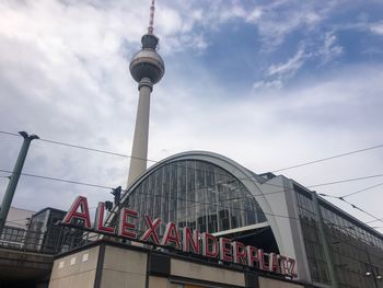 Low angle view of communications tower and building against sky