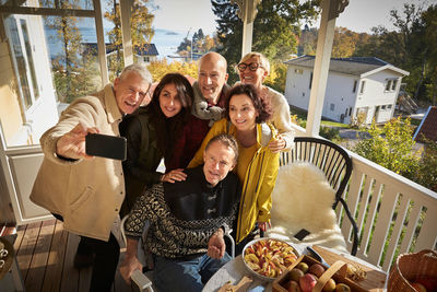 High angle view of happy mature man taking selfie with friends on porch