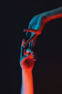 Cropped image of people touching fingers against black background