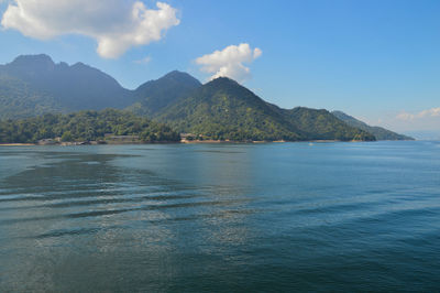 Scenic view of sea and mountains against blue sky