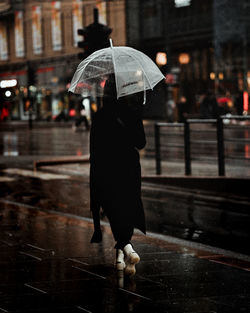 Full length of woman walking on wet street during monsoon