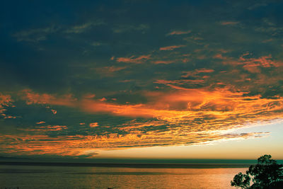 Scenic view of sea against dramatic sky during sunset