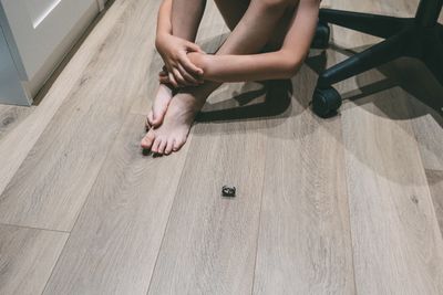 Low section of man sitting by chair on floor