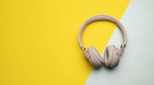 Pink wireless headphones on a gray-yellow background, top view. modern gadget for listening to music
