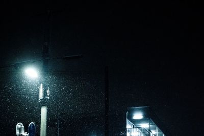 Low angle view of illuminated street light against building at night