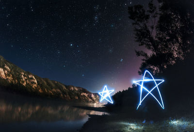 Light painting by lake against sky at night