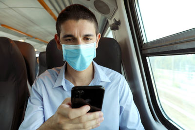 Portrait of young woman using mobile phone in bus