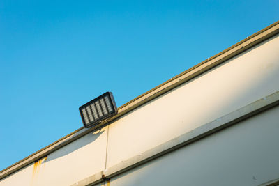 Low angle view of floodlight on building against clear blue sky