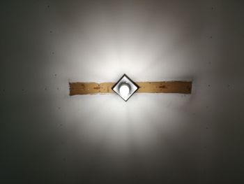 Low angle view of illuminated lamp on wall