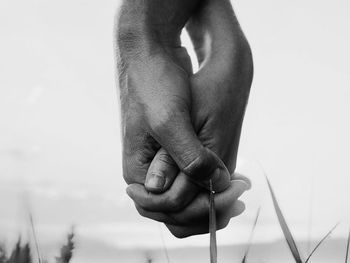 Cropped hand of woman holding cigarette against white background