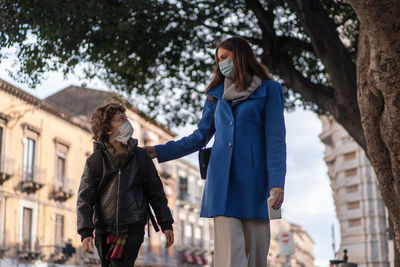 A young mother accompanies her son to school on the street.