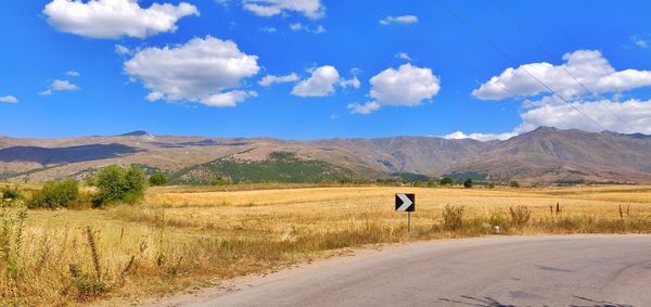 Road amidst field against sky