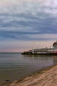 Pier on sea against cloudy sky