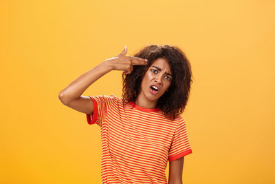 Portrait of smiling woman gesturing against colored background