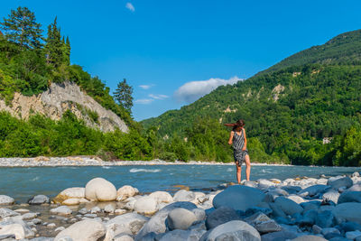 Man standing on rocks by mountain against sky