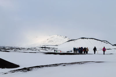 People skiing on snowcapped mountain against clear sky