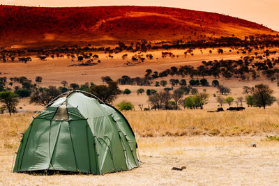 View of tent on landscape during sunset