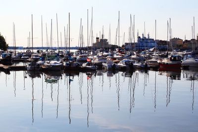 Sailboats moored at harbor against clear sky