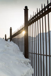 Snow covered railing against sky during winter