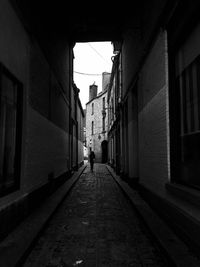 One person walking on narrow alley / footpath amidst buildings in city 