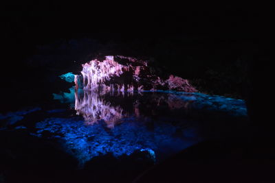Illuminated rock formation in sea